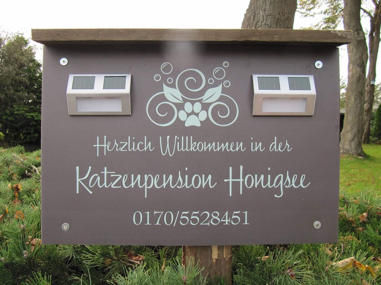 Willkommensschild der Katzenpension Honigsee im grünen Vorgarten